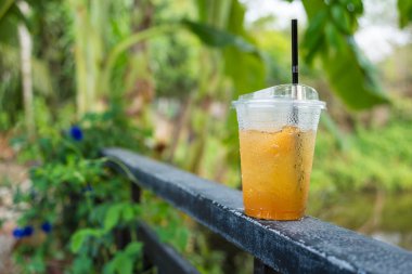 Bir bardak şeftalili buzlu çay, birbiri ardına buzlu, çite bırakılmış.