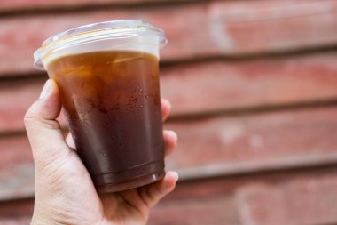 Şeffaf şeffaf bir Amerikano. Plastik bardağı insan elinin üzerine koy.