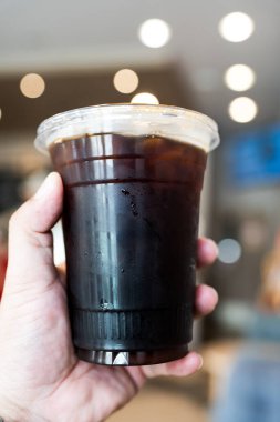 Kahve dükkanında elinde buzlu kahve tutan bir adam.