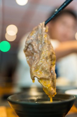 Elinizde çubuk ve kaynamış sığır eti ile çırpılmış çiğ yumurtaya batırılmış siyah kâse.