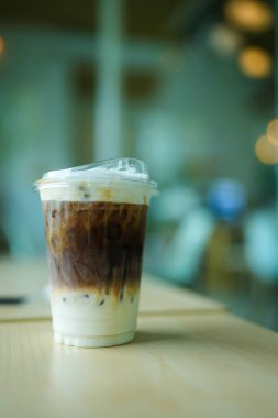 Ahşap masada plastik bardakta buzlu karamel macchiato..