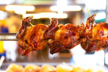 Fırında ızgara tavuk çevirmesi. Bütün tavuk şişleri ızgara yaparken ve mangal yaparken paslanmaz çelik bir şişe yerleştirilmiş. Seçici odak