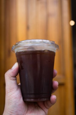 Plastik bardaktaki buzlu kahveyi kapat ya da ahşap arka planda Americano..