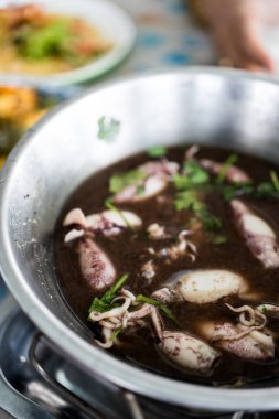 Siyah çorbada bir kase mürekkep balığı. Tayland deniz ürünleri