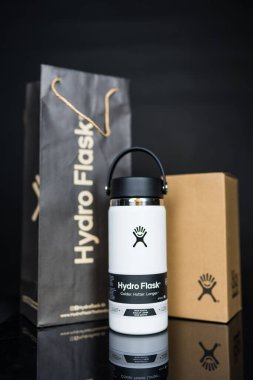 Bangkok, Tayland - 28 Mayıs 2025: Kahverengi paket ve siyah kese kağıdıyla beyaz bir su şişesi. Metal içecek kabı, çevresel ürün.