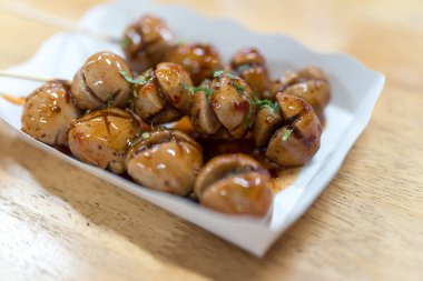 Karton kutuda servis edilen tatlı ve acı soslu Tayland bifteği köftesi şişleri.