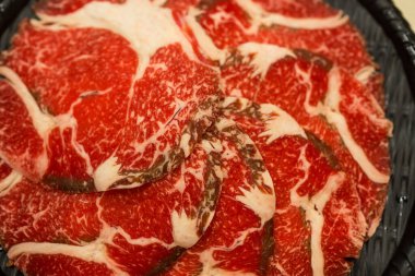 Çiğ et siyah bir kabın içine yerleştirilmiş, sıcak tencere ve ızgara için mükemmel..