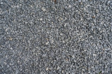 Koyu ve açık gri kaba taşlar, benzer büyüklükteki bir taş çukurunda ezilmiş ve kırılmış. Renkler ve şekiller çok düzensiz..