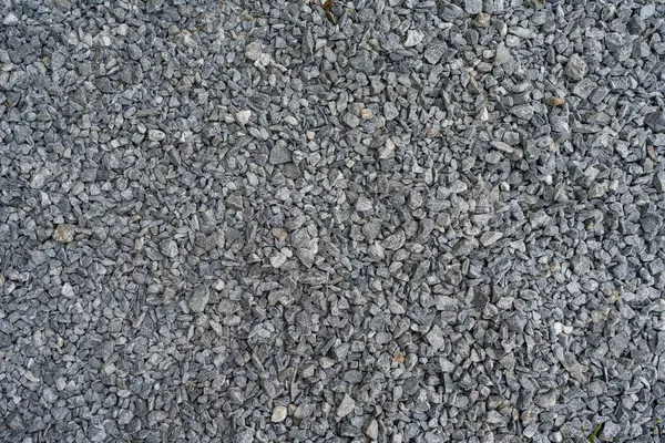 Koyu ve açık gri kaba taşlar, benzer büyüklükteki bir taş çukurunda ezilmiş ve kırılmış. Renkler ve şekiller çok düzensiz..