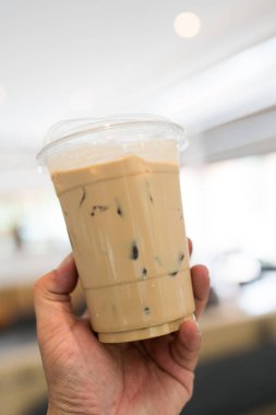 Buzlu espresso, temiz plastik bardakta, insan elinin üzerinde.