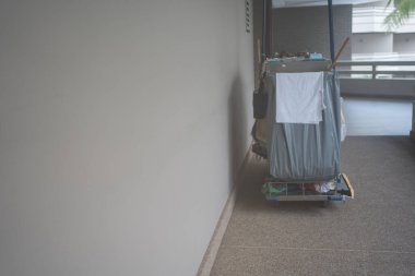 Otel koridoru boyunca araba. İçinde oda malzemeleri ve temizlik malzemeleri olan bir araba.