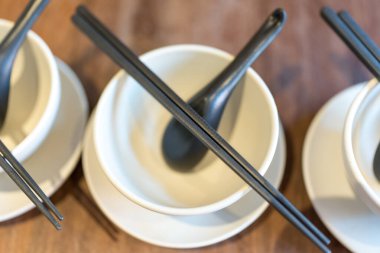 Boş beyaz kaseler, siyah yemek çubukları ve siyah kaşık. Üst görünüm