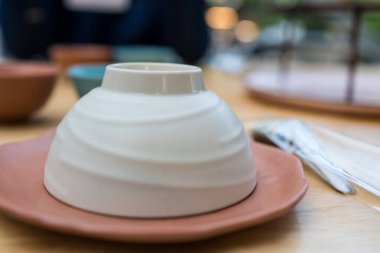 Ahşap masadaki restoranda kullanılmaya hazır seramik kaseyi ters çevirin.