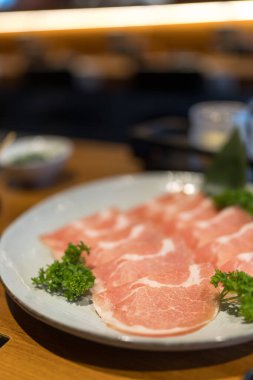 Sukiyaki veya shabu yapmak için yuvarlak tabakta dilimlenmiş domuz eti.