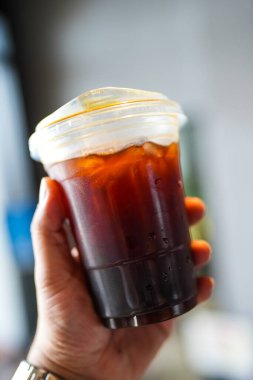 Elinde plastik bir fincan buzlu kahve tutan birinin kısa görüntüsü..