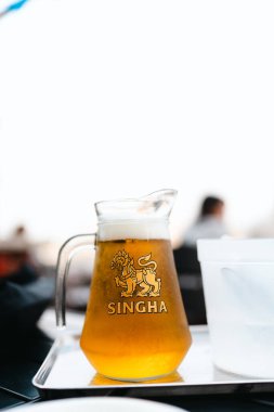 Bangkok, Tayland - 9 Haziran 2025 SINGHA Thai birası, Cool sürahi, orijinal Tayland birası. Bu, Bangkok siluetine karşı ülkede çok popüler bir yerel bira.