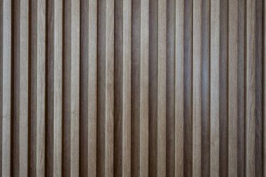 Dar, eşit aralıklı ahşap levhalardan oluşan tekrar eden bir deseni gösteren dikey bir duvar veya bölmenin yakın görüntüsü..
