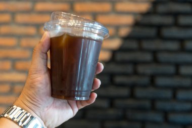 Plastik bardakta buzlu Americano insan eline yakın.