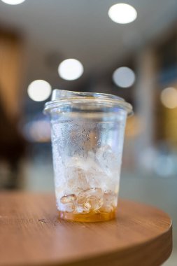 Kafedeki ahşap masada içtikten sonra bardakta biraz buz ve kahve kaldı.