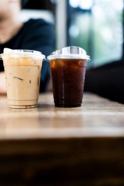 Buz americano ve latte ahşap masada.