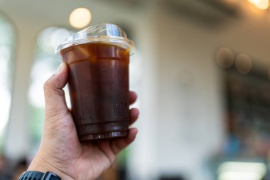 Elinizde plastik bir bardak Americano kahvesi var.