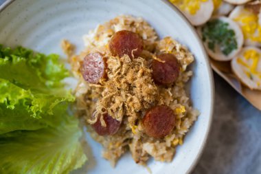 Kızarmış pirinç, dilimlenmiş Çin sosisi ve beyaz kasede kurutulmuş domuz eti..