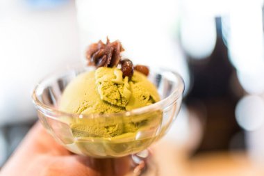 Kibrit yeşili çay dondurması bir cam kasede güzelce sunulur, kırmızı fasulye ezmesiyle süslenir, iştah açıcıdır.