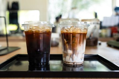 Siyah tepside servis edilen kafede iki bardak buzlu kahve ve buzlu Americano.