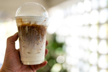 Elindeki plastik bardakta buzlu karamel macchiato.
