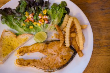 Kızarmış patates kızartması ve salatayla servis edilen mükemmel ızgara somon. Üst görünüm