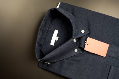 Koyu mavi klasik, siyah arka planda kırmızı kağıt etiketli düzgün katlanmış gömlek..