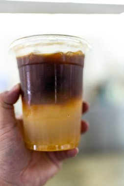 Elinde plastik bardakta buzlu yuzu kahvesi..