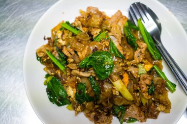 Beyaz tabakta servis edilen soya soslu geniş erişteli lahana ve yumurta..