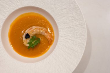 Beyaz kasede servis edilen karidesli kremalı çorba. Üst görünüm