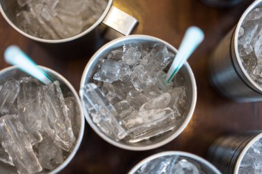 Ahşap masasında saman olan paslanmaz bardakta buz.