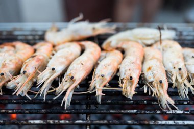Tay nehri karidesleri kömür ızgarasının üzerinde ızgarada kızartılıyor ve iki tarafı da eşit derecede pişiriliyor. Tayland yemeğinin çok lezzetli bir parçası..