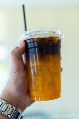 Elinde portakal suyu olan buzlu sade kahve. Espresso, şeffaf bardakta buzlu taze portakal suyu. Yaz modası ferahlatıcı kahve içeceği.