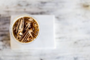 Buzlu Americano 'lu bir kahve fincanı en az beyaz ahşap arka plana yerleştirilir. Tam üstten.