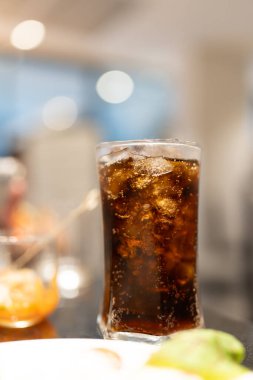 Buzlu içecek şeffaf bir bardakta bulanık bir arkaplan karşısında şeffaf bir buzla tazeleniyor