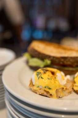 Güzel bir kaplanmış yumurta Benedict mükemmel haşlanmış yumurta üst pastırma ve bol Hollandaise soslu kızarmış İngiliz keki.