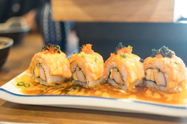 Baharatlı sosla kaplı lezzetli suşi somonları, tabakta servis edilen yüksek lezzetliler.