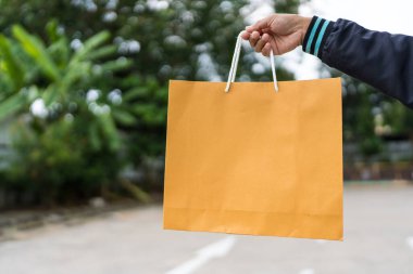 Bir sağ el kahverengi bir kese kağıdına yapışır, beyaz sapları sergilenir.