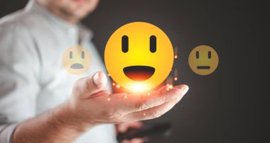 Geri bildirim yapan bir kişi farklı yüz ifadelerinden sarı bir gülen yüz seçer. Müşteri memnuniyeti anket konsepti. Ürün kalitesi geri bildirim değerlendirmesinde müşteri değerlendirmesi