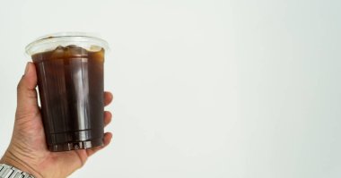 Beyaz beton duvara yaslanmış plastik bir bardak Americano 'nun yakın görüntüsü.