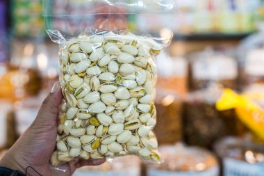 Elinde vakumlu plastik torbayla kavrulmuş ve tuzlanmış fıstık.