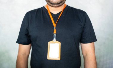 Personel personelinde turuncu ipli boş bir kimlik kartı. Siyah günlük gömlekli..