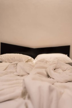 Buruşuk otel yatağı, yatalak çarşaflar, yapılmamış çarşaflar ve kullanımdan sonra misafir konaklama yeri gösteren dağınık yastıklar.