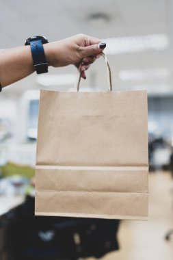 Elinde kahverengi kağıt bir alışveriş çantası tutan bir kadın.