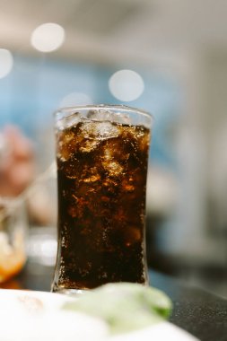 Buzlu bir bardakta, bulanık bir arka planda serin ve davetkar bir ferahlatıcı sunan alkolsüz içecek..