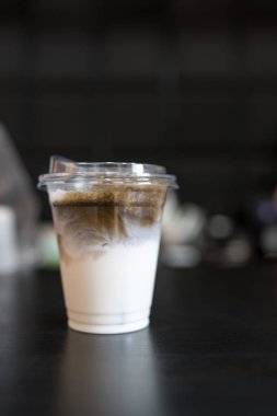Plastik bardakta buzlu kömür latte. İçkinin dokusunu ve ferahlatıcı görünüşünü gösteriyor.